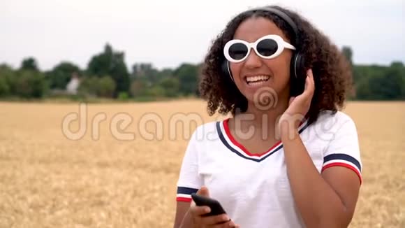 非洲裔美国少女少女听无线耳机和智能手机音乐视频的预览图