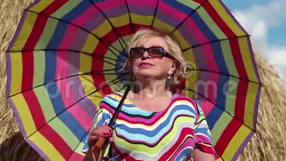 戴眼镜的金发女人带着色彩鲜艳的伞视频的预览图