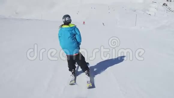 滑雪者用弯曲的脚在斜坡上滑行晴天滑雪胜地雪山视频的预览图