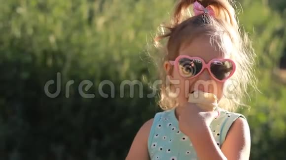 在阳光明媚的夏天小女孩戴着太阳镜吃冰淇淋视频的预览图
