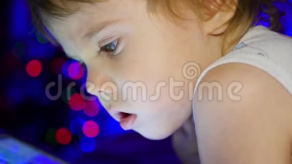 孩子看着躺在床上的药片背景中圣诞杉木的灯光和花环视频的预览图