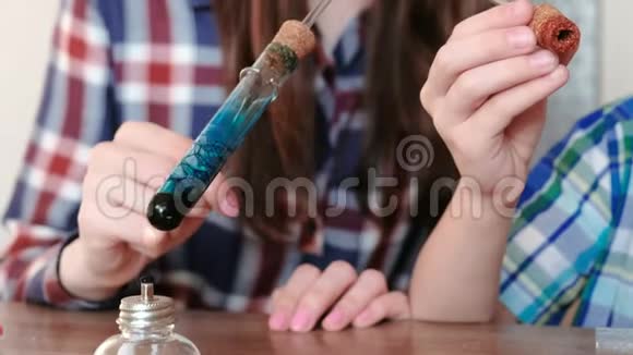 家庭化学实验男孩和他妈妈在燃烧的酒精灯上用蓝色液体加热试管这就是视频的预览图