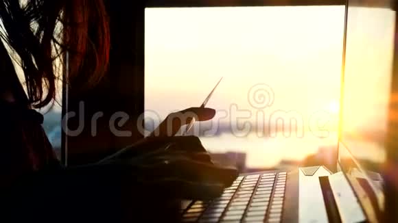在美丽的夕阳下一位女士在城市背景模糊的背景下使用信用卡上网她的笔记本电脑在美丽的阳光下运行视频的预览图