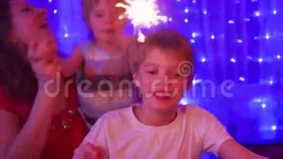 幸福的家庭在聚会上点燃了火花背景中圣诞杉木的灯光和花环视频的预览图