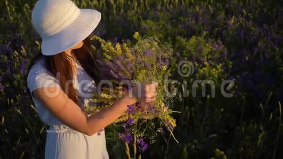 年轻的女人带着一束田野的花走着视频的预览图