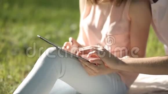 那个和那个女孩坐在公园里看平板电脑的家伙特写镜头视频的预览图
