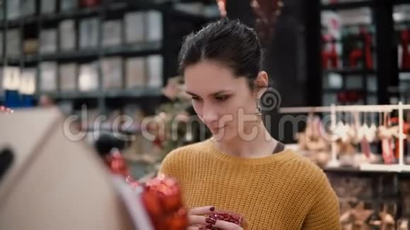 年轻漂亮的黑发女孩在商店选择明亮的红色圣诞装饰视频的预览图