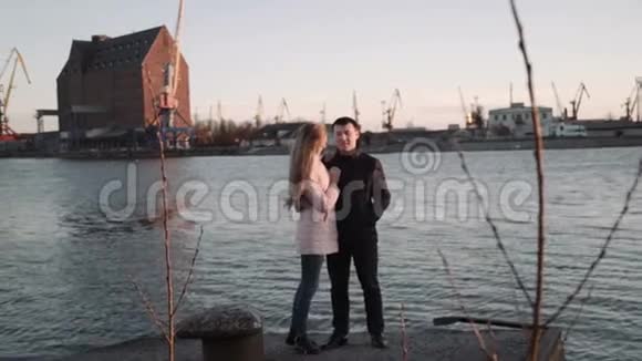 迷人的浪漫情侣看着港口里的船在海港散步享受美丽的日落视频的预览图