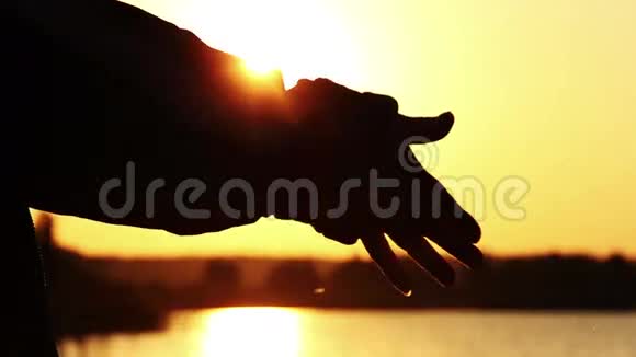 牵着手在河的夕阳下母亲在黎明时牵着孩子的手视频的预览图