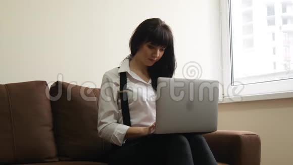 坐在沙发上用笔记本电脑的年轻女子视频的预览图