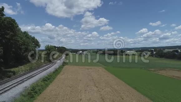 在美丽的阳光明媚的夏日用铁轨俯瞰农田和乡村视频的预览图