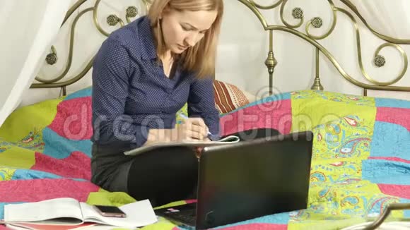 漂亮的学生在她的笔记本电脑上工作家庭在线教育视频的预览图