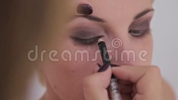近距离射击化妆师在模特的整个眼睛周围涂眼线视频的预览图