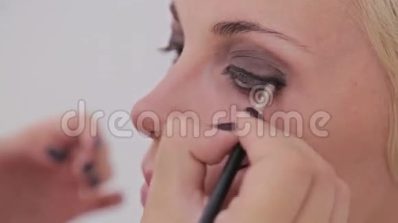 近距离射击化妆师在模特的整个眼睛周围涂眼线视频的预览图