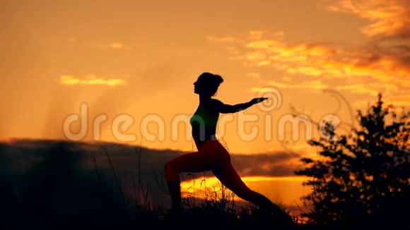 一位健身女性的剪影在日出时伸展背景是太阳视频的预览图