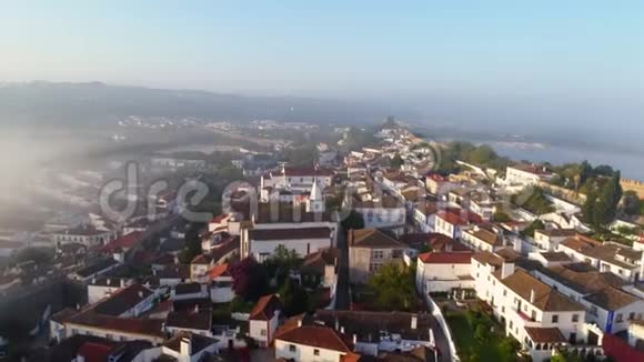 雾蒙蒙的早晨带着美丽的小镇奥比多斯的空中景观视频的预览图