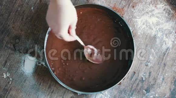 一个女人把巧克力面团倒在烤盘里然后把它弄平视频的预览图