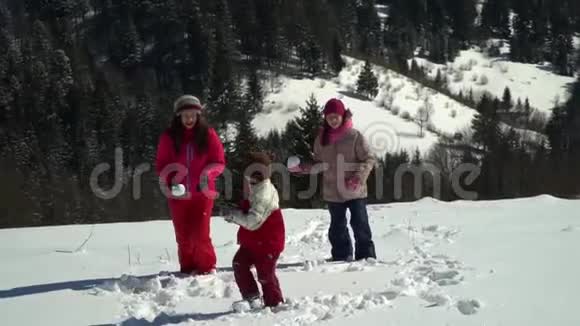 快乐的一家人在冬天的雪山上玩得很开心妈妈和她的两个孩子扔雪球视频的预览图