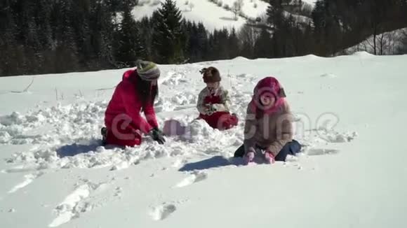 快乐的一家人在冬天的雪山上玩得很开心妈妈和她的两个孩子扔雪球视频的预览图