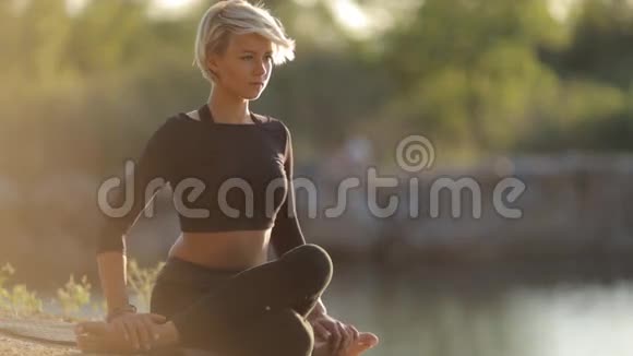 穿着黑色衣服在湖岸做瑜伽的少女视频的预览图