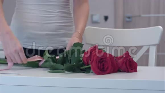 年轻女子在红玫瑰花束上系丝带蝴蝶结视频的预览图