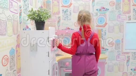 玩玩具厨房的女孩打开烤箱视频的预览图