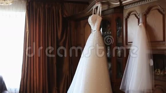 可爱的白色婚纱挂在窗边的木架背景上视频的预览图