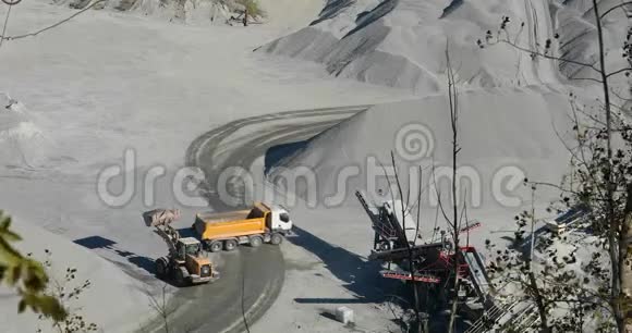 采石场的推土机把一块石头装到一辆自卸卡车的车身上一辆黄色的推土机在一个采石场工作装载一个自卸汽车视频的预览图