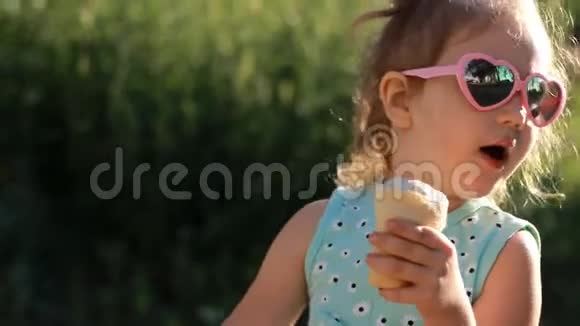 在阳光明媚的夏天小女孩戴着太阳镜吃冰淇淋视频的预览图