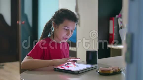 少女正在吃三明治在平板电脑上玩一个网络游戏女孩社交媒体平板电脑互联网视频的预览图