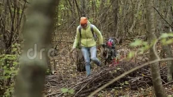 母亲和女儿穿着温暖的夹克走在秋天的森林里视频的预览图