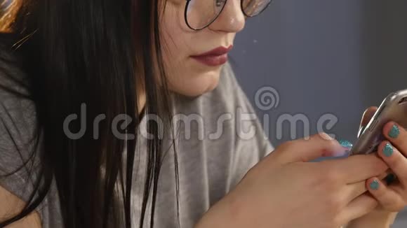 带眼镜的年轻女人在智能手机上浏览照片反射在眼镜里视频的预览图