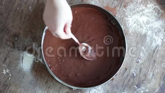 一个女人把巧克力面团倒在烤盘里然后把它弄平视频的预览图