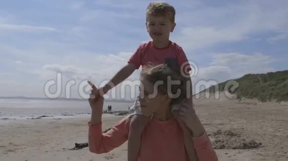 年轻的母子沿着海滩散步视频的预览图