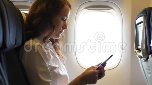 忙碌的女人在飞机上有智能手机视频的预览图