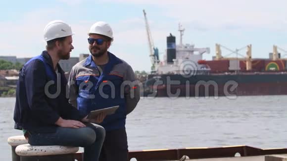两名带笔记本电脑的工程师微笑着在船运货物港进行交流视频的预览图