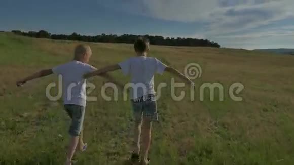两个快乐的孩子在公园里跑来跑去在田野上两兄弟正在日落时分玩耍视频的预览图