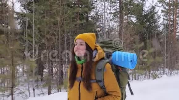 女游客走在冬天的森林路上肩上背着一个背包视频的预览图