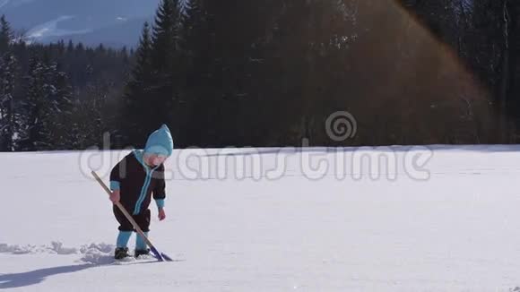 小女孩用雪铲撒雪的慢动作视频的预览图