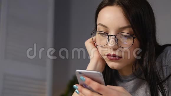 带眼镜的年轻女人在智能手机上浏览照片反射在眼镜里视频的预览图