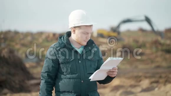 工程师在挖掘机背景下讲电话看文件和打电话视频的预览图