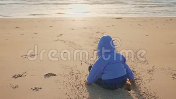 宝宝的生活方式一个男孩在天然海滩上玩沙子和石头视频的预览图