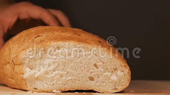 面包师正在用菜刀在木制的表面上切一片刚出炉的面包视频的预览图