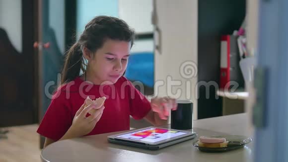 少女正在吃三明治在平板电脑上玩一个网络游戏女孩社交媒体平板电脑互联网视频的预览图