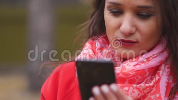 年轻女子在电话短信和户外聊天上浏览互联网视频的预览图