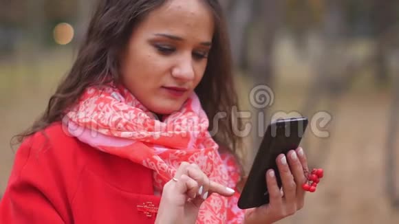 年轻女子在电话短信和户外聊天上浏览互联网视频的预览图