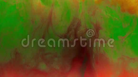 彩色的黄色墨水滴从上面混合在水中轻轻地在水下旋转背景上有红色和绿色的墨水视频的预览图