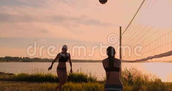 一群年轻女孩在日落或日出时打沙滩排球视频的预览图