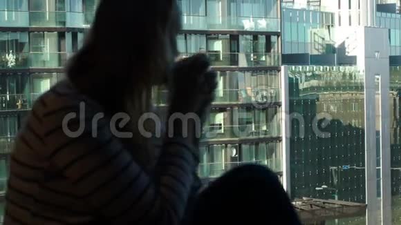 窗前的女人拿着杯子看着城市视频的预览图
