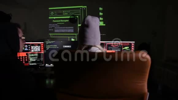 在黑暗的房间里在显示屏幕上使用数据代码的计算机上工作的男性和女性黑客视频的预览图
